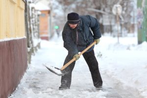 man shoveling snow on sidewalk