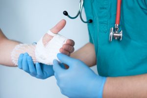 close up of doctor bandaging one hand after an accident