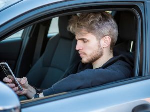 mid-20s man texting while driving