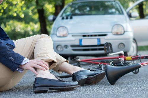 A person rubs their injured ankle after a bicycle accident.