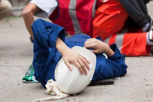 A man lays on the ground injured after a construction accident.