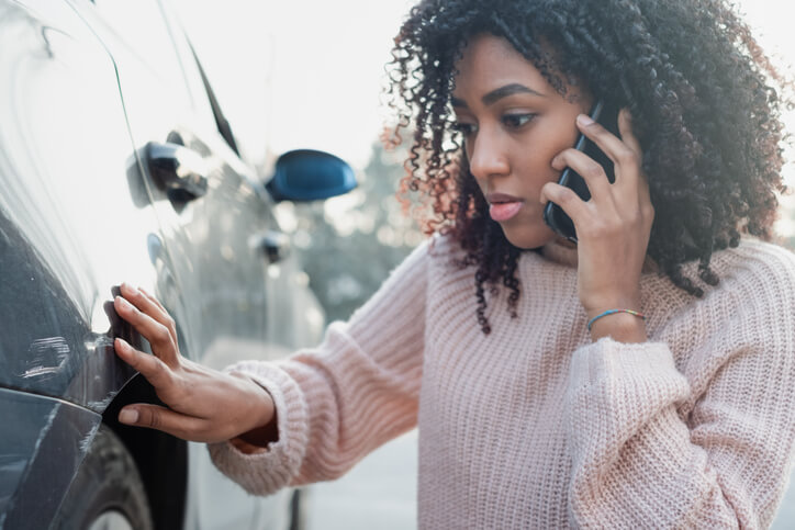 woman examining her car after a car accident